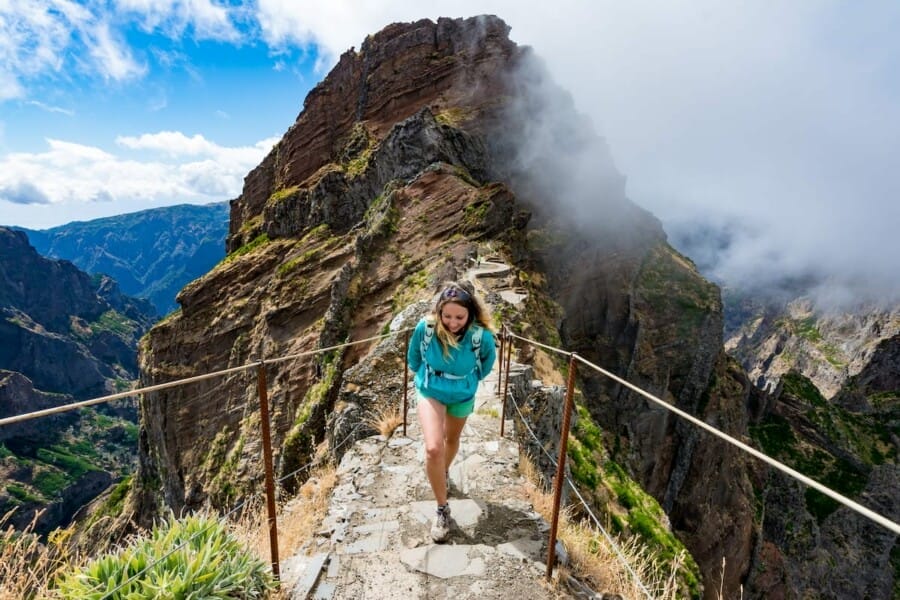 A woman on a stair case on a mountain top surrounded by clouds.