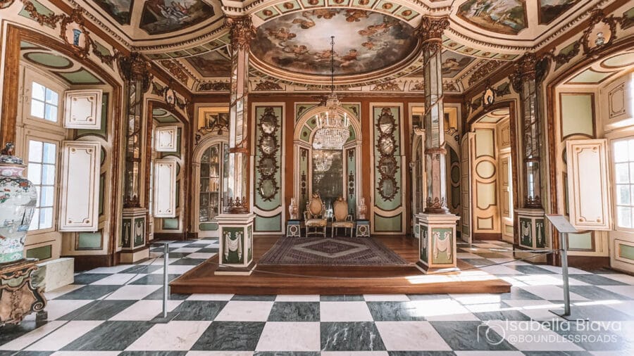 Ornate Rococo interior with detailed frescoes, chandeliers, and decorative pillars. Features intricate designs and luxurious decor, likely a historical palace room.