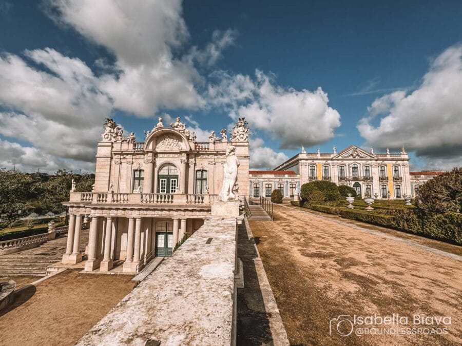 Two grand Baroque-style buildings stand under a partly cloudy sky. Ornate facades and statues adorn the picturesque setting, enhancing its historical ambiance.
